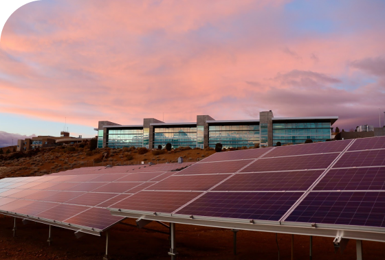 A rooftop solar system in front of a building at sunset, demonstrating that Utilizer are expert energy consultants.