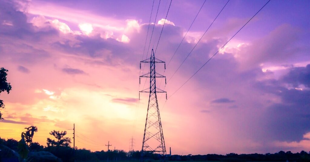 An electrciity tower in a field at sunset
